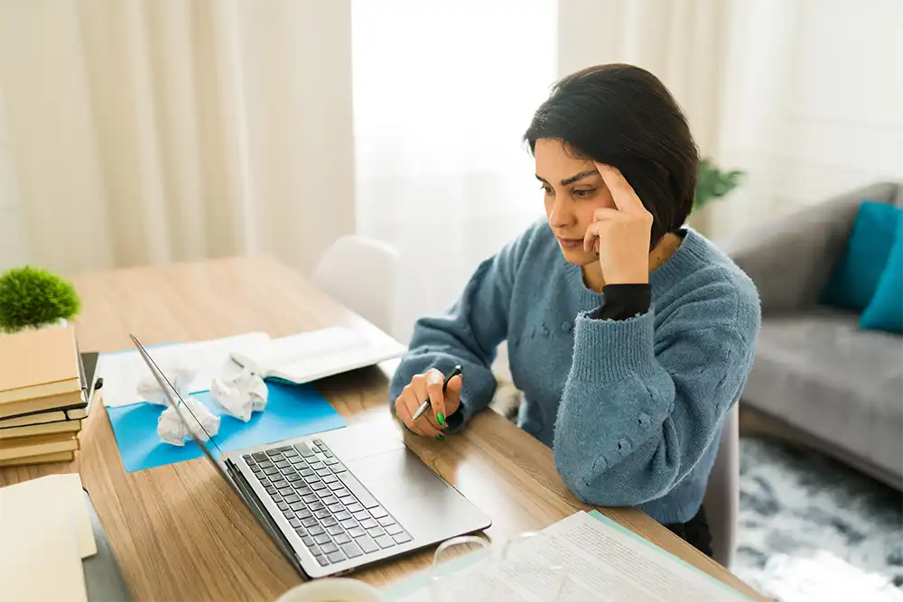 Frustrated female writer experiencing creative block, typing on laptop while sitting at home
